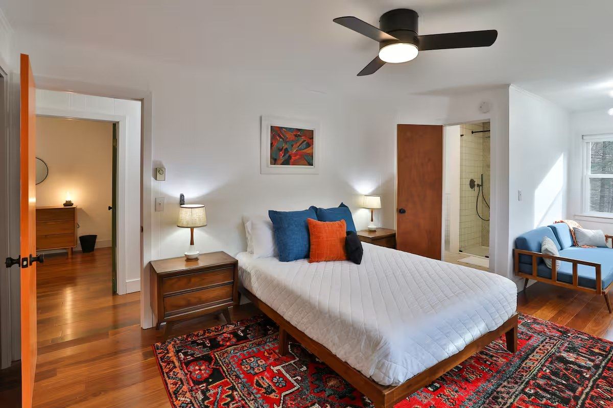 Second bedroom with blue and orange pillows and an en-suite bathroom