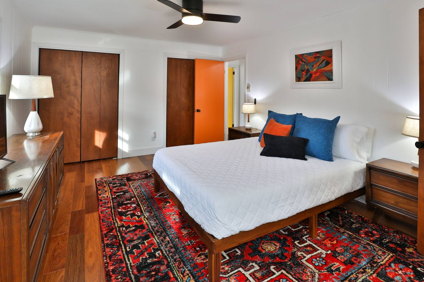 Third bedroom with a bold orange closet door and abstract art