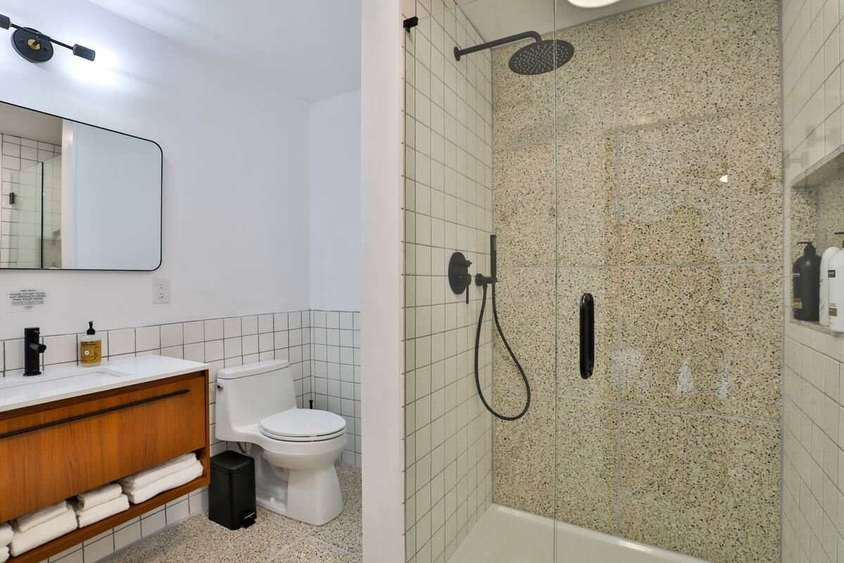 Renovated bathroom with terrazzo tile shower and walnut vanity