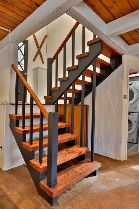 Open wood and steel staircase with a laundry room below